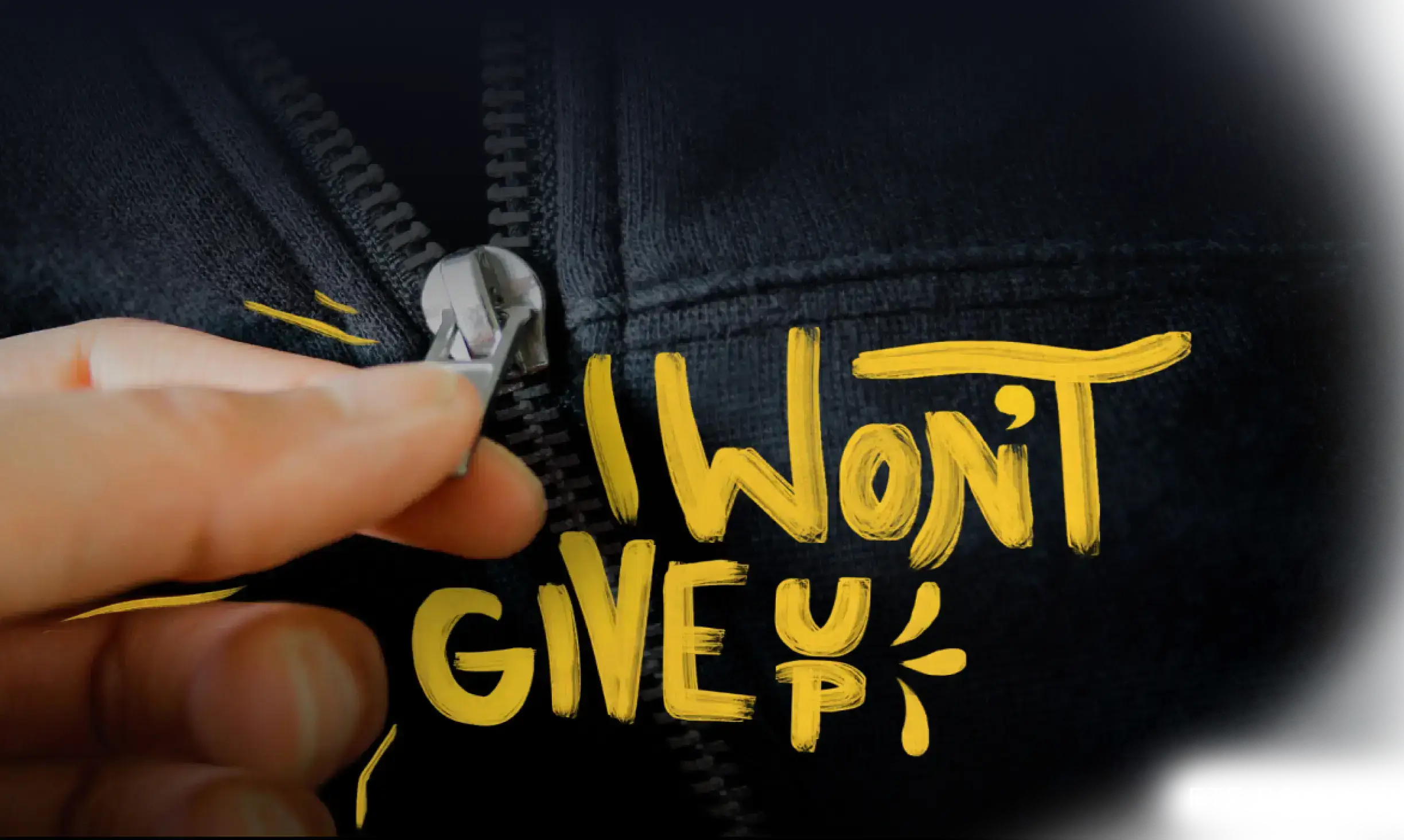 Someone zipping up a coat with the words "I won't give up" on the chest."